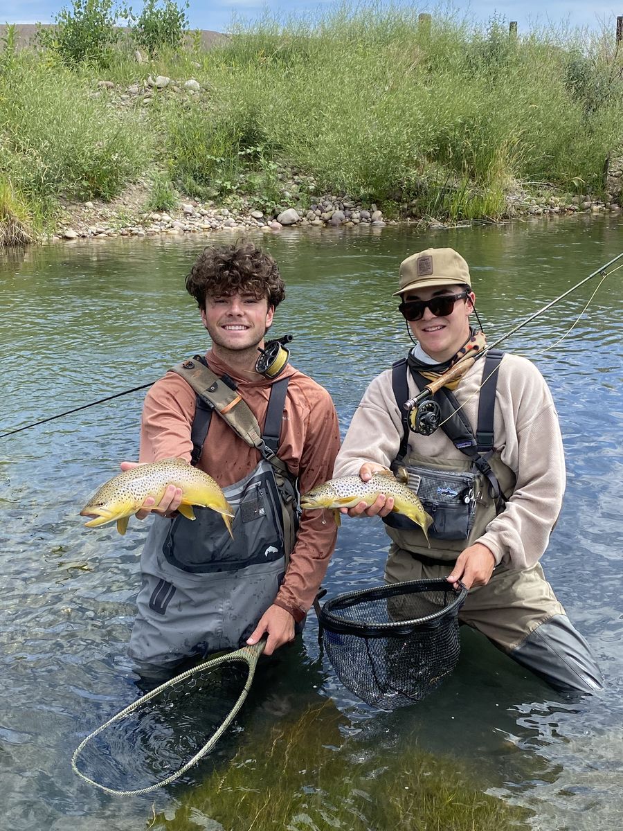Two anglers kneeling with a brown trout